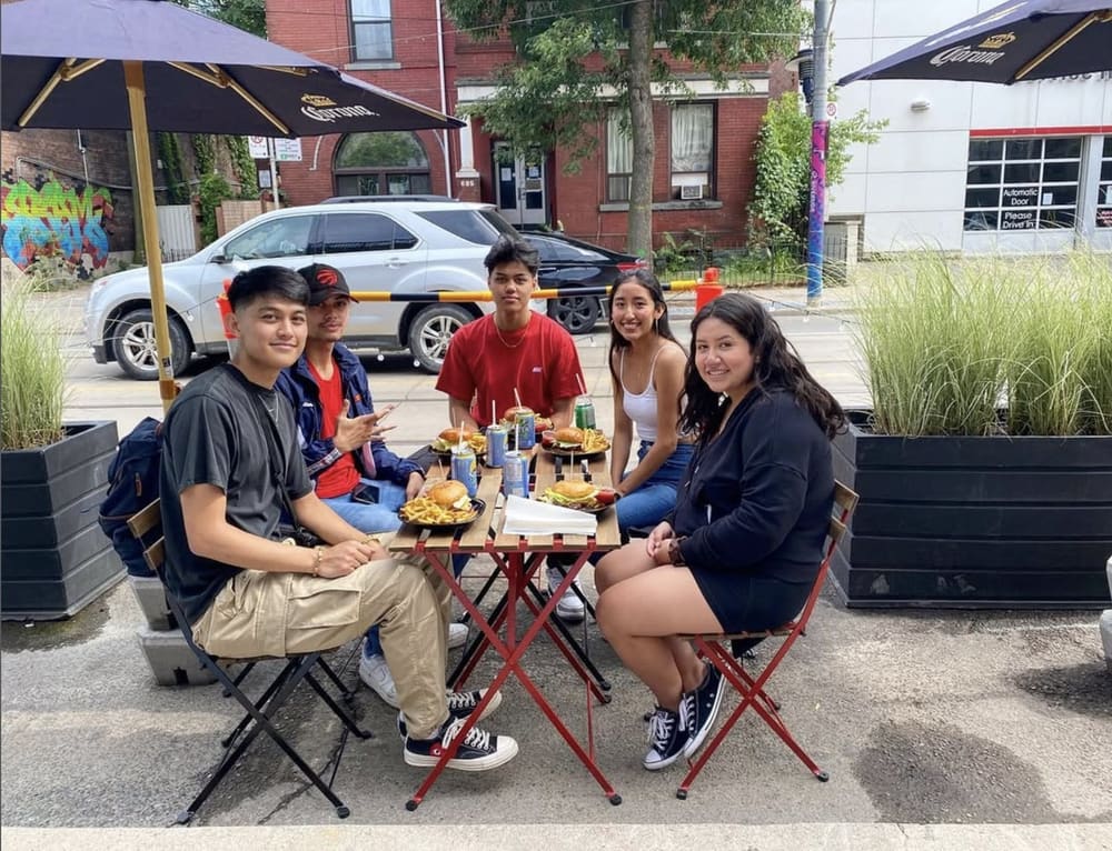 Customers sharing burgers at the patio tables on Queen Street East