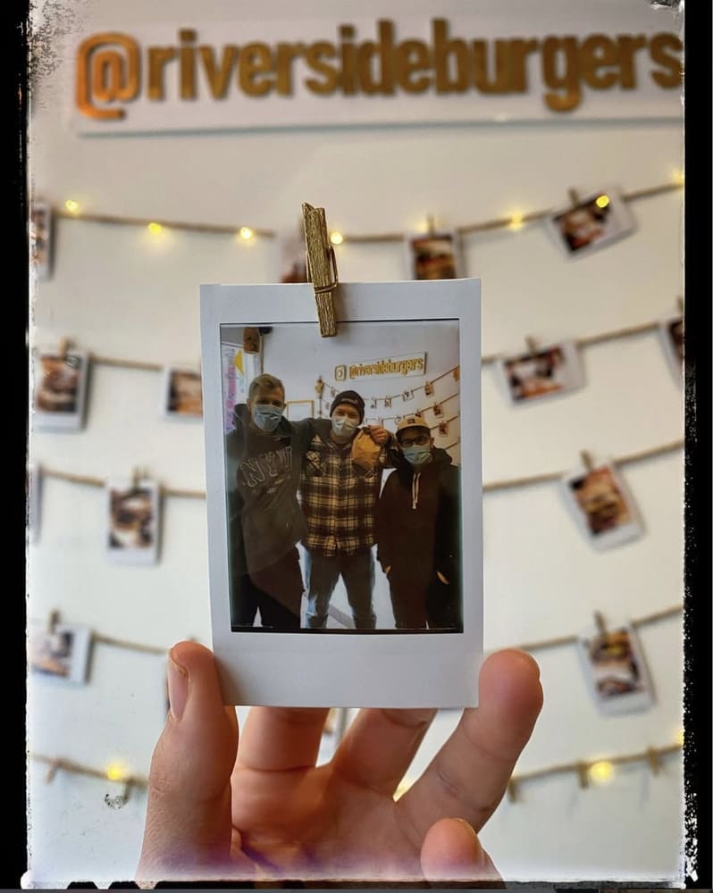 A polaroid held up in front of the instant photo wall inside the shop